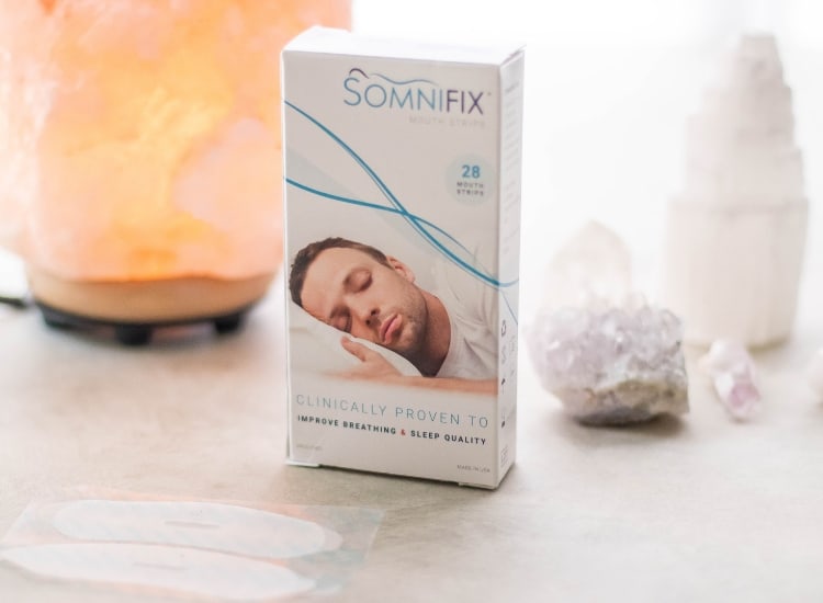 box of Somnifix mouth tape for mouth taping, along with crystals and a salt lamp on a grey background.