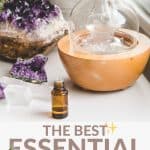 A glass diffuser and essential oil bottle on a white table with a amethyst geode crystal. The words "best essential oil brands" are listed below.