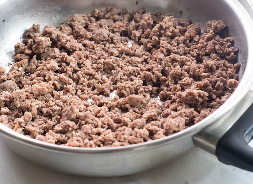 A stainless steel skillet full of cooked ground beef.