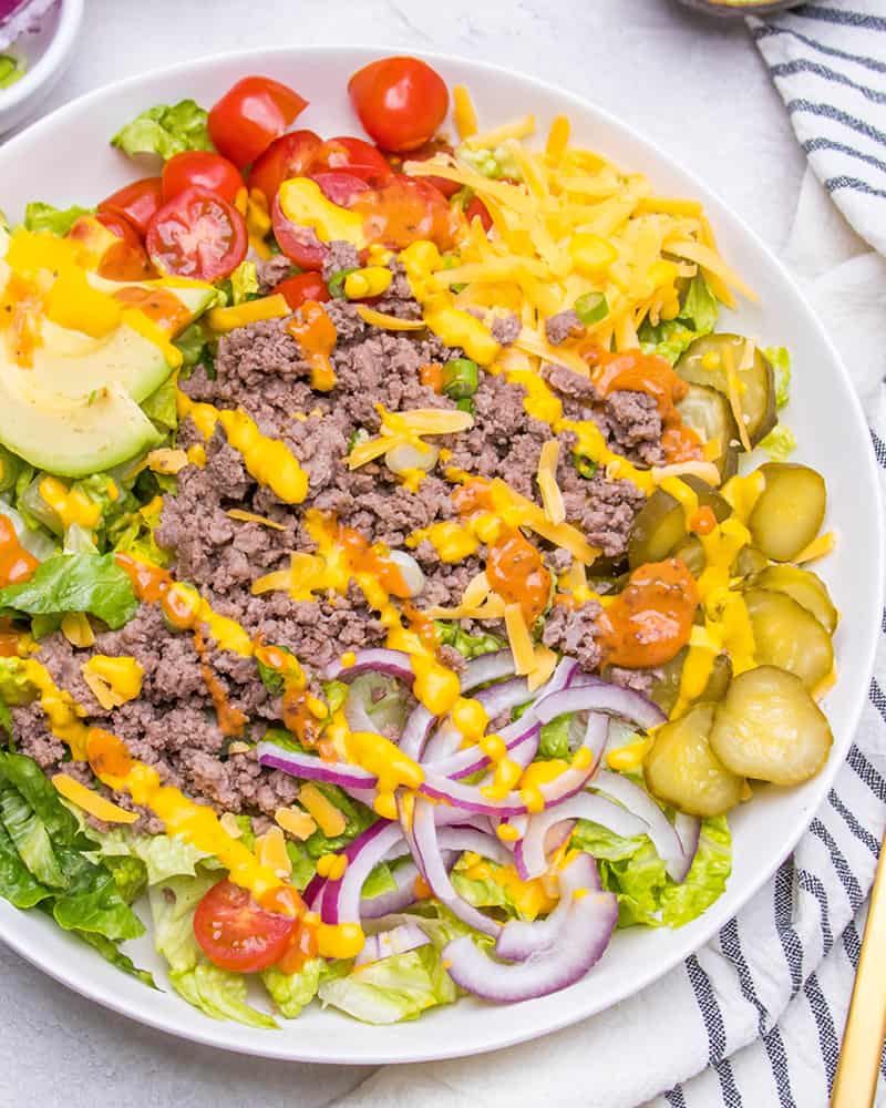 A Big Mac Salad burger bowl with cheese, dressing, and ground beef on a marble table.