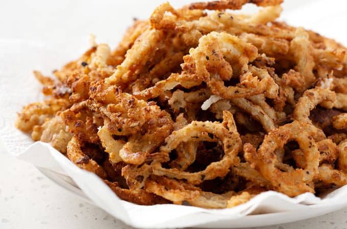 A bowl of gluten free french fried onion rings on a quartz white countertop.