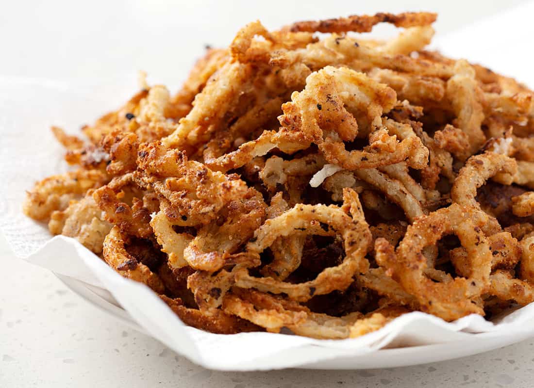 A bowl of gluten free french fried onion rings on a quartz white countertop.