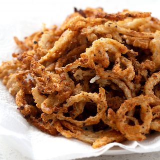 A bowl of gluten free french fried onion rings on a white counter.