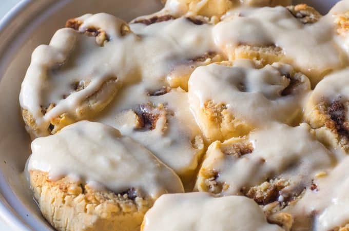 A pie pan of gluten free and paleo cinnamon rolls covered in warm frosting.