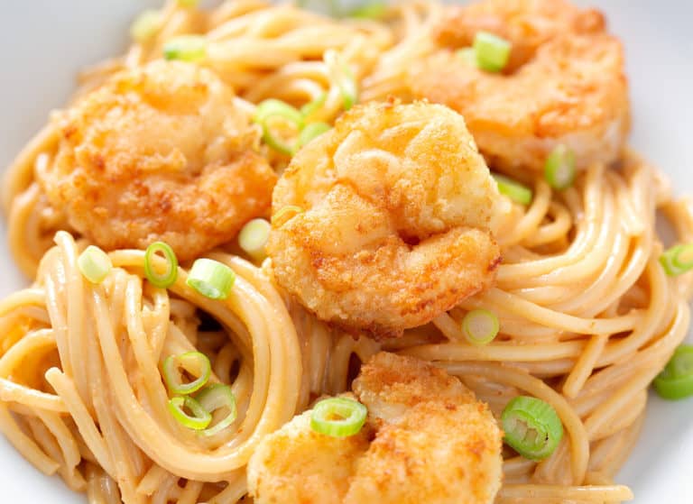 A close up image of a bowl of Bang Bang Fried Shrimp Pasta with green onions as a garnish.
